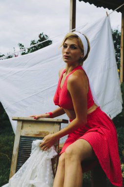 Kurutulmuş çamaşır. Genç, güzel, seksi bir kadın güneşli bir günde çamaşırlarını yıkar ve iç çamaşırlarını dışarı asar. Kırmızı elbiseli..