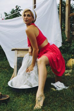 Kurutulmuş çamaşır. Genç, güzel, seksi bir kadın güneşli bir günde çamaşırlarını yıkar ve iç çamaşırlarını dışarı asar. Kırmızı elbiseli..