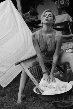 Kurutulmuş çamaşır. Genç, güzel, seksi bir kadın güneşli bir günde çamaşırlarını yıkar ve iç çamaşırlarını dışarı asar. Kırmızı elbiseli..