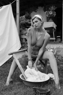 Kurutulmuş çamaşır. Genç, güzel, seksi bir kadın güneşli bir günde çamaşırlarını yıkar ve iç çamaşırlarını dışarı asar. Kırmızı elbiseli..