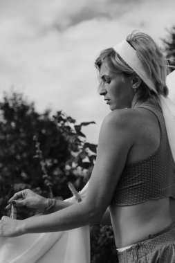 Kurutulmuş çamaşır. Genç, güzel, seksi bir kadın güneşli bir günde çamaşırlarını yıkar ve iç çamaşırlarını dışarı asar. siyah beyaz fotoğraf.