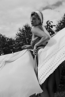 Kurutulmuş çamaşır. Genç, güzel, seksi bir kadın güneşli bir günde çamaşırlarını yıkar ve iç çamaşırlarını dışarı asar. siyah beyaz fotoğraf.