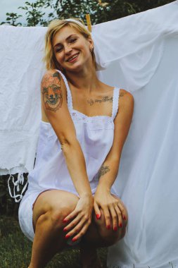 Kurutulmuş çamaşır. Genç ve güzel bir kadın, güneşli bir günde elbiselerini yıkar ve dışarı asar..