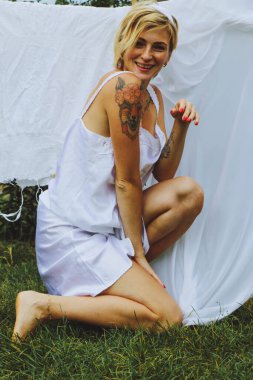 Kurutulmuş çamaşır. Genç ve güzel bir kadın, güneşli bir günde elbiselerini yıkar ve dışarı asar..