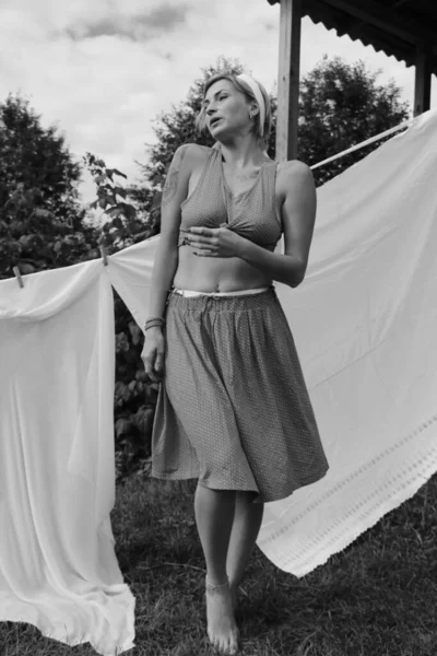 干洗的衣服在阳光明媚的日子里 年轻而性感的女人在花园里洗衣服 还把内裤挂在外面 黑白照片 — 图库照片