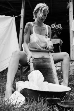 Kurutulmuş çamaşır. Genç, güzel, seksi bir kadın güneşli bir günde çamaşırlarını yıkar ve iç çamaşırlarını dışarı asar. siyah beyaz fotoğraf.