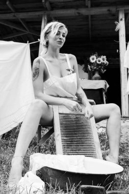 Kurutulmuş çamaşır. Genç, güzel, seksi bir kadın güneşli bir günde çamaşırlarını yıkar ve iç çamaşırlarını dışarı asar. siyah beyaz fotoğraf.