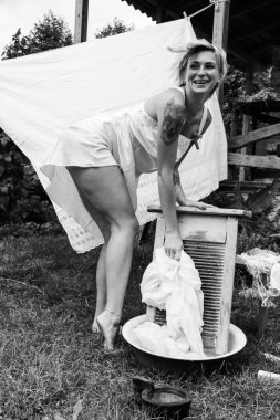Kurutulmuş çamaşır. Genç, güzel, seksi bir kadın güneşli bir günde çamaşırlarını yıkar ve iç çamaşırlarını dışarı asar. siyah beyaz fotoğraf.