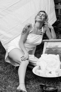 Kurutulmuş çamaşır. Genç, güzel, seksi bir kadın güneşli bir günde çamaşırlarını yıkar ve iç çamaşırlarını dışarı asar. siyah beyaz fotoğraf.