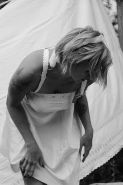 Kurutulmuş çamaşır. Genç, güzel, seksi bir kadın güneşli bir günde çamaşırlarını yıkar ve iç çamaşırlarını dışarı asar. siyah beyaz fotoğraf.