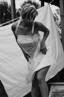 Kurutulmuş çamaşır. Genç, güzel, seksi bir kadın güneşli bir günde çamaşırlarını yıkar ve iç çamaşırlarını dışarı asar. siyah beyaz fotoğraf.