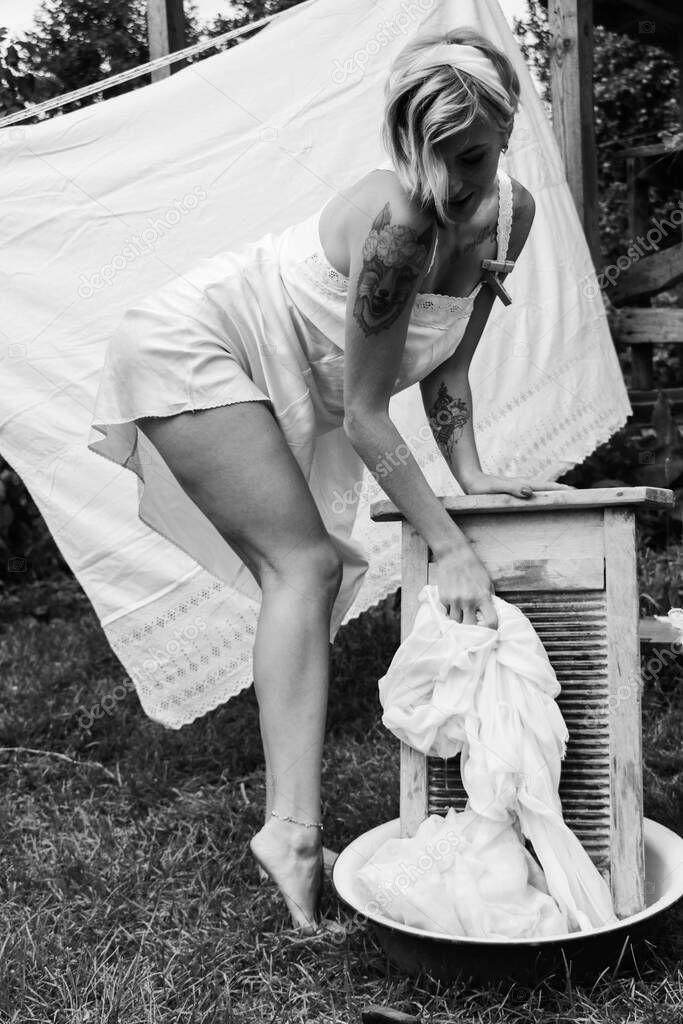 Dried laundry. Young beautiful sexy woman washes clothes and hangs underwear outdoors on a sunny day with a garden. black and white photo.