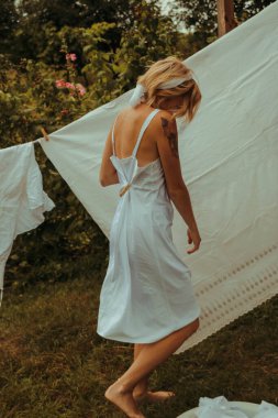 Kurutulmuş çamaşır. Genç, güzel, seksi bir kadın güneşli bir günde çamaşırlarını yıkar ve iç çamaşırlarını dışarı asar. siyah beyaz fotoğraf.