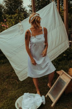 Kurutulmuş çamaşır. Genç, güzel, seksi bir kadın güneşli bir günde çamaşırlarını yıkar ve iç çamaşırlarını dışarı asar. siyah beyaz fotoğraf.