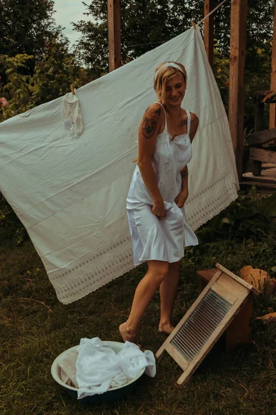 洗濯物を干した 若い美しいセクシーな女性は服を洗い 庭と晴れた日に屋外で下着を掛けます 白黒写真です — ストック写真