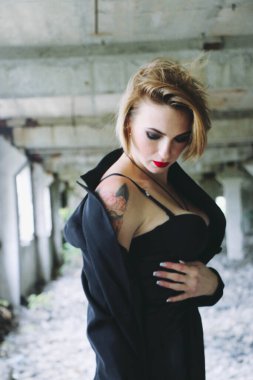 Parlak makyajlı, siyah deri etekli güzel bir kadın. Drama kraliçesi, anksiyete gerilimi, harabeler içinde bir yerde