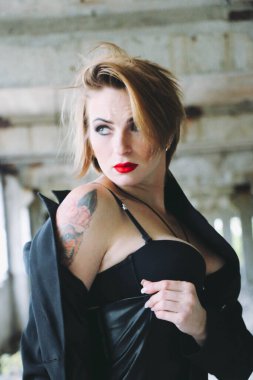 Parlak makyajlı, siyah deri etekli güzel bir kadın. Drama kraliçesi, anksiyete gerilimi, harabeler içinde bir yerde