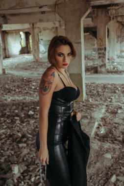 Parlak makyajlı, siyah deri etekli güzel bir kadın. Drama kraliçesi, anksiyete gerilimi, harabeler içinde bir yerde