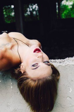 Güzel, genç bir kadın, parlak makyajlı, siyah korseli ve taytlı sarışın, seksi, grunge stili, dramatik, harap olmuş bir yerde penceresi olan.