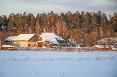 Kış manzarası karlı dağlar, barınak ve vadi mavi gökyüzü, gün batımı. Eski evler, çitler ve yollar. Putivsk köyü, Chernigov olast, Ukrayna