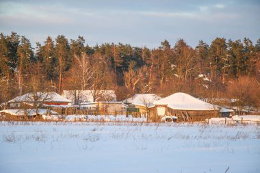 Kış manzarası karlı dağlar, barınak ve vadi mavi gökyüzü, gün batımı. Eski evler, çitler ve yollar. Putivsk köyü, Chernigov olast, Ukrayna
