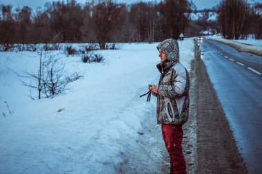 Telefonlu bir adam Zidio 'nun kış günbatımının hızlandırılmış fotoğraflarını çekiyor. Tarla, yol ve ağaçlar karla kaplı..