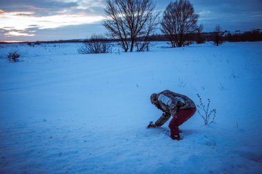 Telefonlu bir adam Zidio 'nun kış günbatımının hızlandırılmış fotoğraflarını çekiyor. Tarla, yol ve ağaçlar karla kaplı..