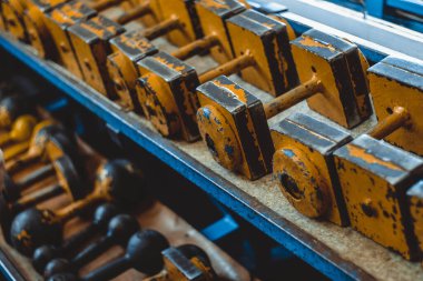 Eski sarı halterler spor salonundaki bir rafta duruyordu. Soyulmuş boya, eski püskü..