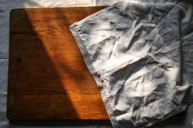 Beyaz keten masa örtüsü ve dantel havlu üzerine eski ahşap tahta. Güneşli doğal ışık, gölge. Mutfak masası manzaralı. Güzel retro, rustik arkaplan, serbest alan.