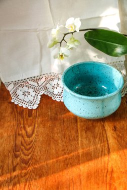 Mocap eski ahşap tahta ve mavi tabak beyaz keten masa örtüsü ve dantel havlu beyaz orkide çiçeği, güneş ışığı doğal ışık, gölge. Mutfak masası. Hoş retro, rustik arkaplan, boş alan.