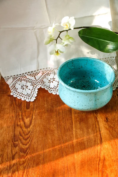 Mocap eski ahşap tahta ve mavi tabak beyaz keten masa örtüsü ve dantel havlu beyaz orkide çiçeği, güneş ışığı doğal ışık, gölge. Mutfak masası. Hoş retro, rustik arkaplan, boş alan.