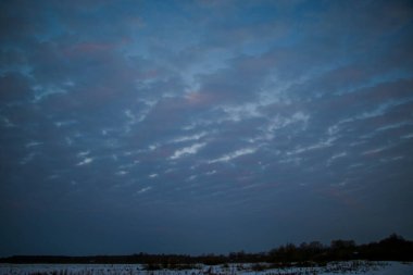 Telefonlu bir adam Zidio 'nun kış günbatımının hızlandırılmış fotoğraflarını çekiyor. Tarla, yol ve ağaçlar karla kaplı..