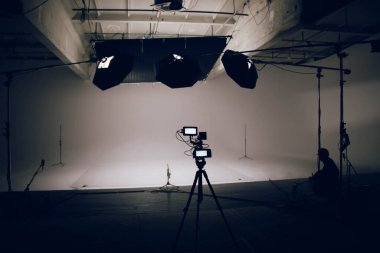 Profesyonel ekipmanların iş için hazırlandığı büyük ve modern bir video stüdyosunun içi. Kamera ön planda.