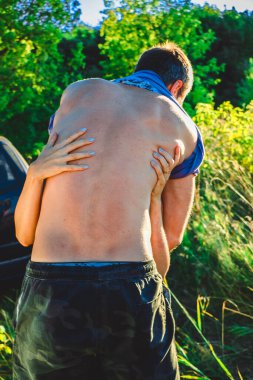 Sırtında kadın elleri olan çıplak genç bir adam. Kadın nazikçe erkeği kucaklıyor. Samimiyet aşkı romantizm