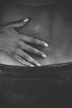 Sırtında kadın elleri olan çıplak genç bir adam. Siyah beyaz fotoğraf. Kadın nazikçe erkeği kucaklıyor. Samimiyet aşkı romantizm