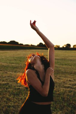 Güneşli bir yaz akşamında, gün batımında, siyah elbiseli genç ve güzel bir esmer. Çekici bir kadın dans ediyor, arka planda biçilmiş buğday gibi poz veriyor..