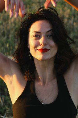 Güneşli bir yaz akşamında, gün batımında, siyah elbiseli genç ve güzel bir esmer. Çekici bir kadın dans ediyor, arka planda biçilmiş buğday gibi poz veriyor..