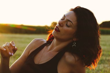 Güneşli bir yaz akşamında, gün batımında, siyah elbiseli genç ve güzel bir esmer. Çekici bir kadın dans ediyor, arka planda biçilmiş buğday gibi poz veriyor..