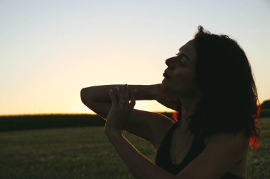 Güneşli bir yaz akşamında, gün batımında, siyah elbiseli genç ve güzel bir esmer. Çekici bir kadın dans ediyor, arka planda biçilmiş buğday gibi poz veriyor..