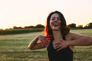 Güneşli bir yaz akşamında, gün batımında, siyah elbiseli genç ve güzel bir esmer. Çekici bir kadın dans ediyor, arka planda biçilmiş buğday gibi poz veriyor..