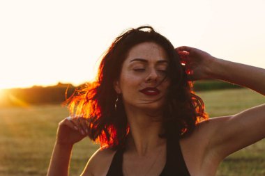 Güneşli bir yaz akşamında, gün batımında, siyah elbiseli genç ve güzel bir esmer. Çekici bir kadın dans ediyor, arka planda biçilmiş buğday gibi poz veriyor..