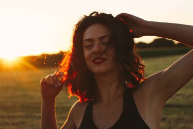 Güneşli bir yaz akşamında, gün batımında, siyah elbiseli genç ve güzel bir esmer. Çekici bir kadın dans ediyor, arka planda biçilmiş buğday gibi poz veriyor..