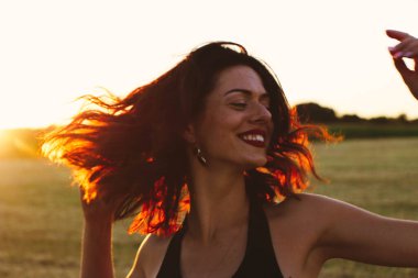 Güneşli bir yaz akşamında, gün batımında, siyah elbiseli genç ve güzel bir esmer. Çekici bir kadın dans ediyor, arka planda biçilmiş buğday gibi poz veriyor..