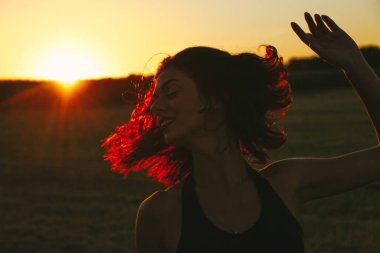 Güneşli bir yaz akşamında, gün batımında, siyah elbiseli genç ve güzel bir esmer. Çekici bir kadın dans ediyor, arka planda biçilmiş buğday gibi poz veriyor..