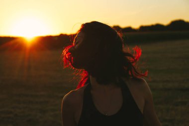 Güneşli bir yaz akşamında, gün batımında, siyah elbiseli genç ve güzel bir esmer. Çekici bir kadın dans ediyor, arka planda biçilmiş buğday gibi poz veriyor..