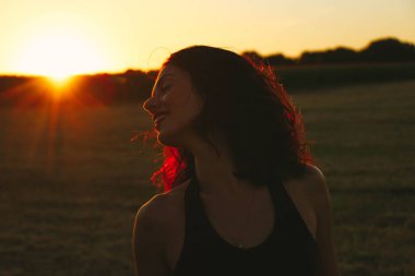 Güneşli bir yaz akşamında, gün batımında, siyah elbiseli genç ve güzel bir esmer. Çekici bir kadın dans ediyor, arka planda biçilmiş buğday gibi poz veriyor..