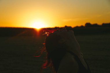 Güneşli bir yaz akşamında, gün batımında, siyah elbiseli genç ve güzel bir esmer. Çekici bir kadın dans ediyor, arka planda biçilmiş buğday gibi poz veriyor..