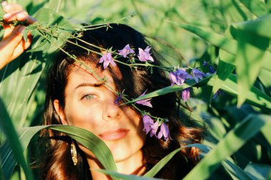 Yazın mısır yaprakları içinde güzel esmer bir kız, doğadaki bir kadının sanat portresi. Kameraya bakarak kahkahalar atmak, seçici keskinlik, açık iş gölgesi doğal ışık.