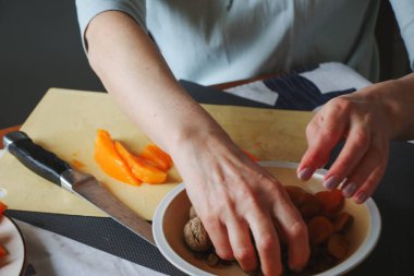 Yakın çekim kadın yetişkinler portakal kabağı ve kuru üzümlere dokunur, ev mutfağında yemek hazırlarlar, normal ev ışığı işlemleri, seçici keskinleştirme.