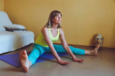 Yetişkin güzel Avrupalı kadın evde yoga yapıyor. Bir dizi yoga pozu. Pashchimottanasana bacakları bükerken sağlıklı yaşam tarzı konsepti, refah kişisel bakım